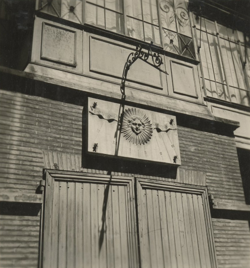 Détail de façade avec cadran solaire disposé au-dessus d’une baie aux volets clos, au premier étage une logette à verrière.
Photographie s’inscrivant dans une collection de 28 vues rassemblées sous le thème des hôtels de la rue Perchepinte et environs.