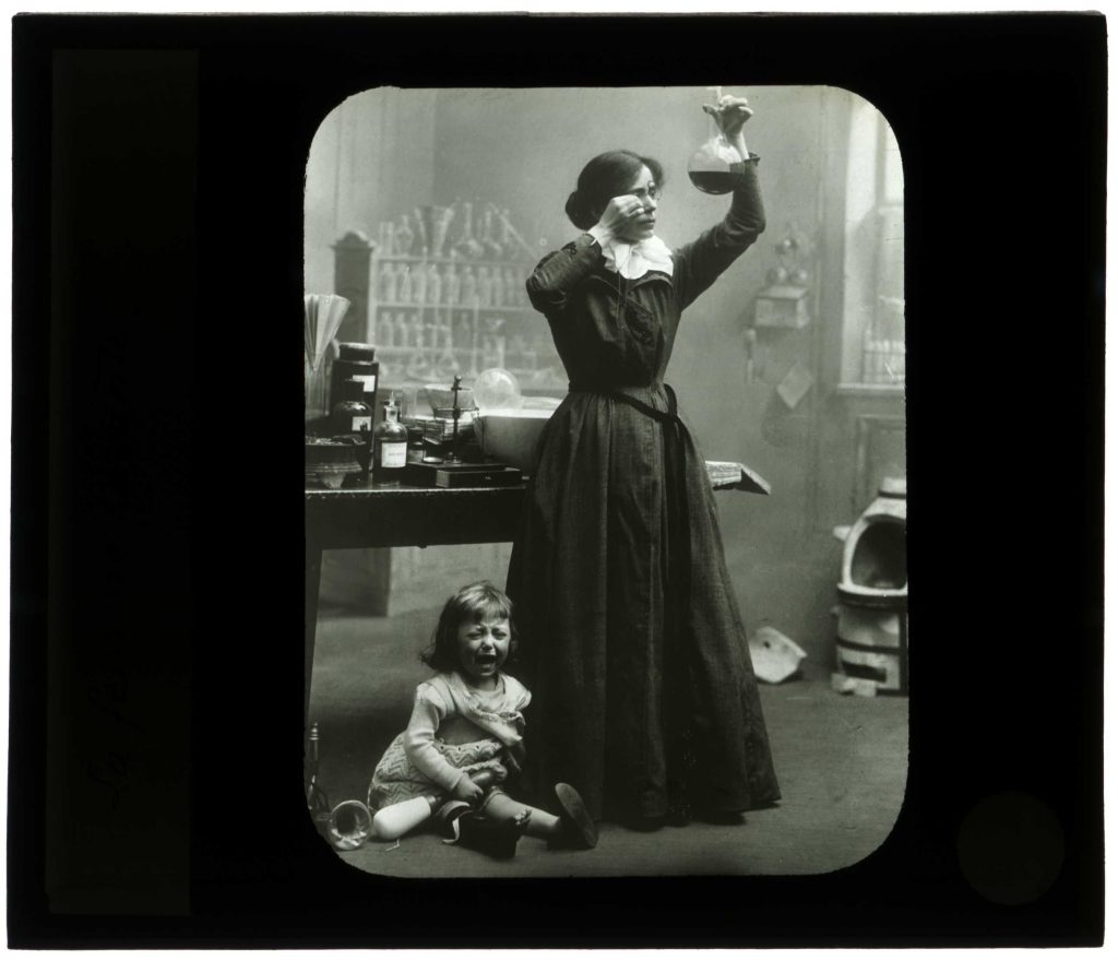 Une femme et une jeune enfant posant dans un laboratoire. Autour d’elles se trouvent une table de travail et du matériel scientifique. Photographie d’Henri Laffont, vers 1900-1910.