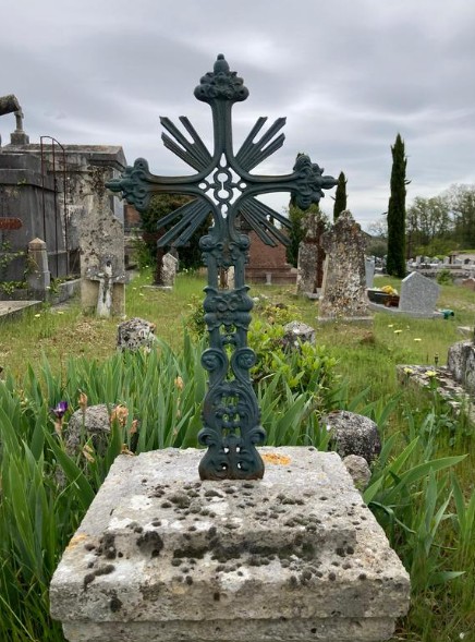 Stèle en pierre et croix en fonte moulée dans l'allée centrale du cimetière de Pibrac.